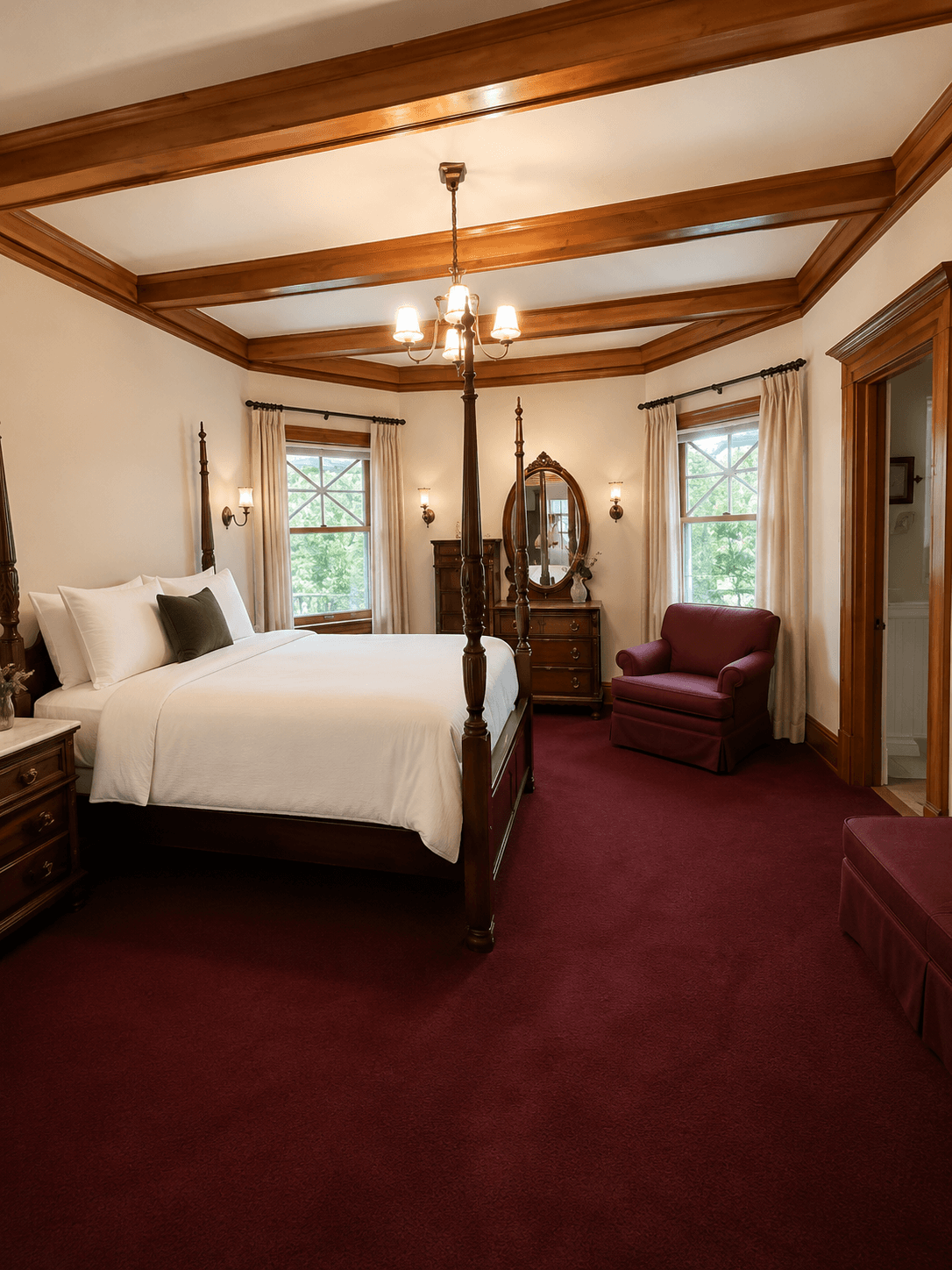 A cozy bedroom featuring a four-poster bed, burgundy carpet, and large windows.