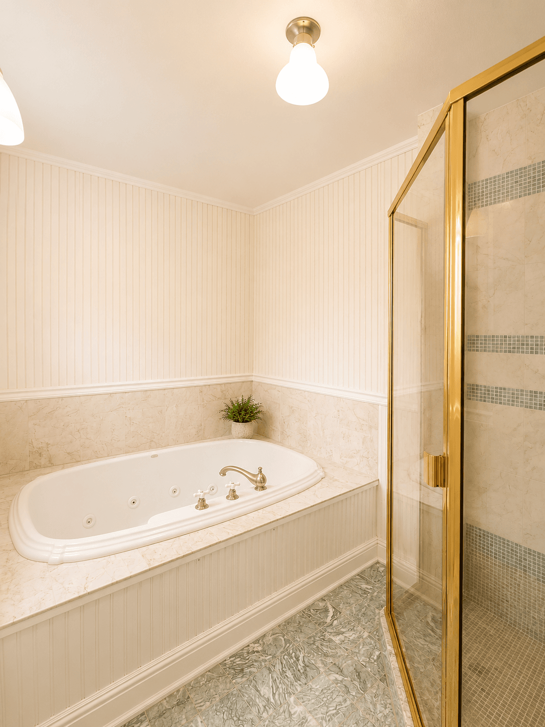 A well-lit bathroom featuring a luxurious bathtub with a gold faucet and a glass shower enclosure.