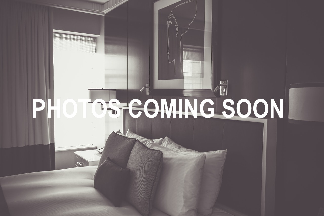 A stylish hotel room interior with a bed and artwork, overlaid with the text "PHOTOS COMING SOON."
