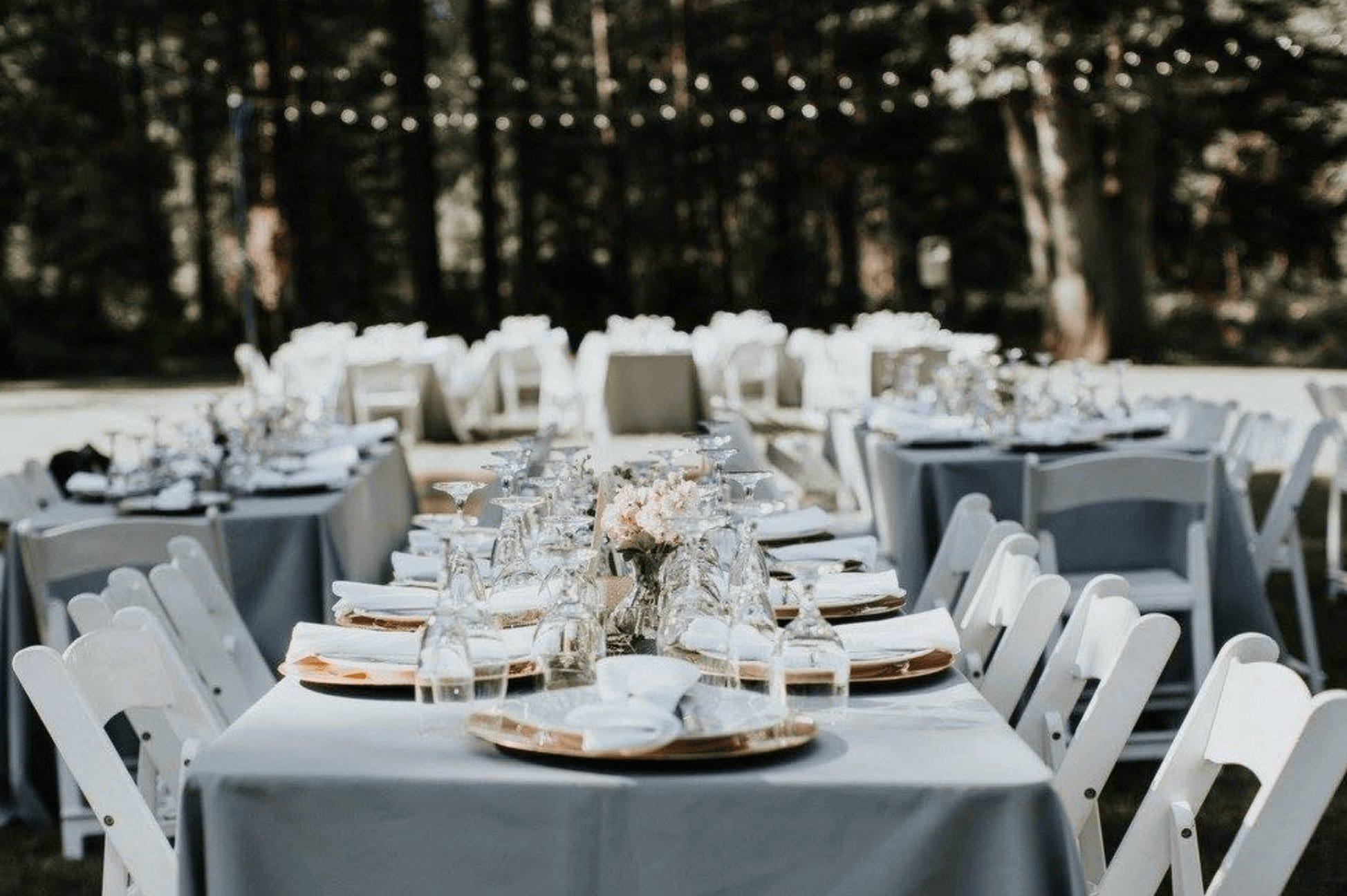 Elegant outdoor dining setup with neatly arranged tables, chairs, and glassware.